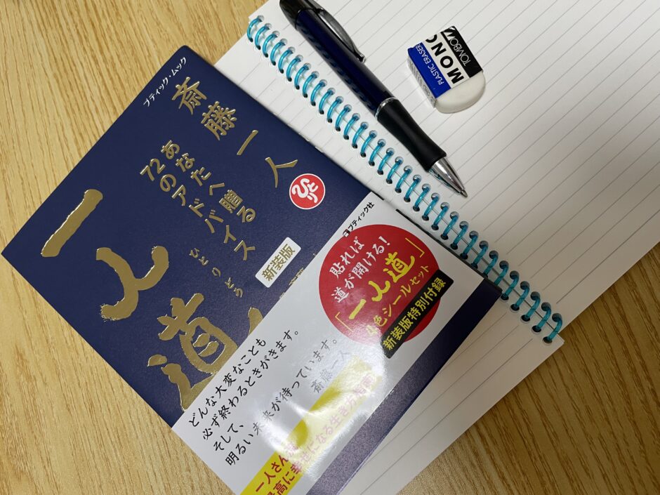 机の上にノートを広げ、その上に本とペンが置かれている写真