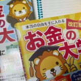 机の上にノートを広げ、その上に本とペンが置かれている写真