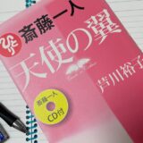 机の上にノートを広げ、その上に本とペンが置かれている写真