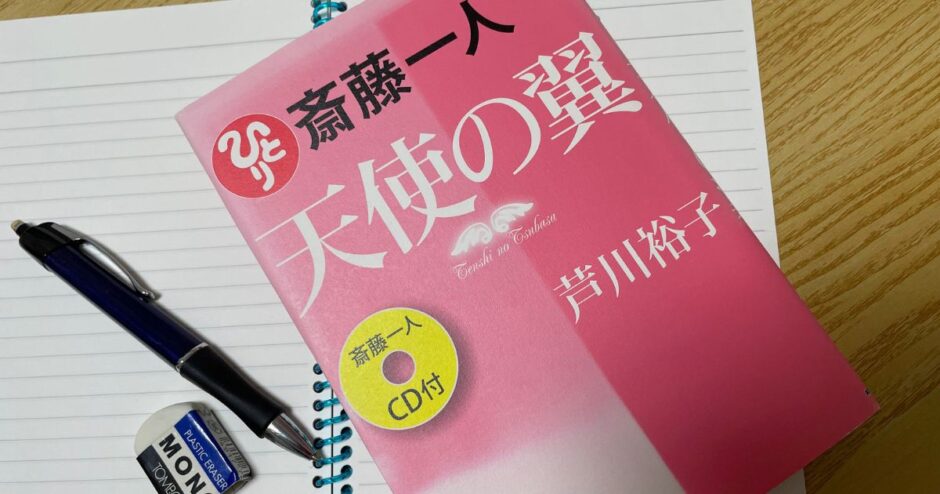 机の上にノートを広げ、その上に本とペンが置かれている写真
